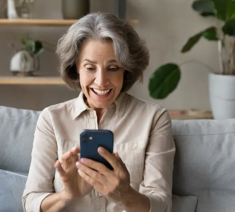 Woman staring at phone, overjoyed at the money she will save on health insurance.